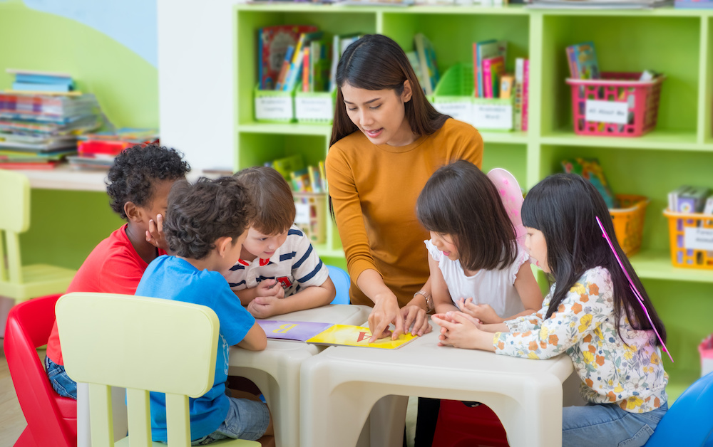 teacher showing book to group of children