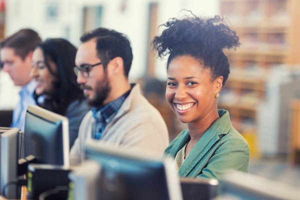 smiling young woman next to young man at computer