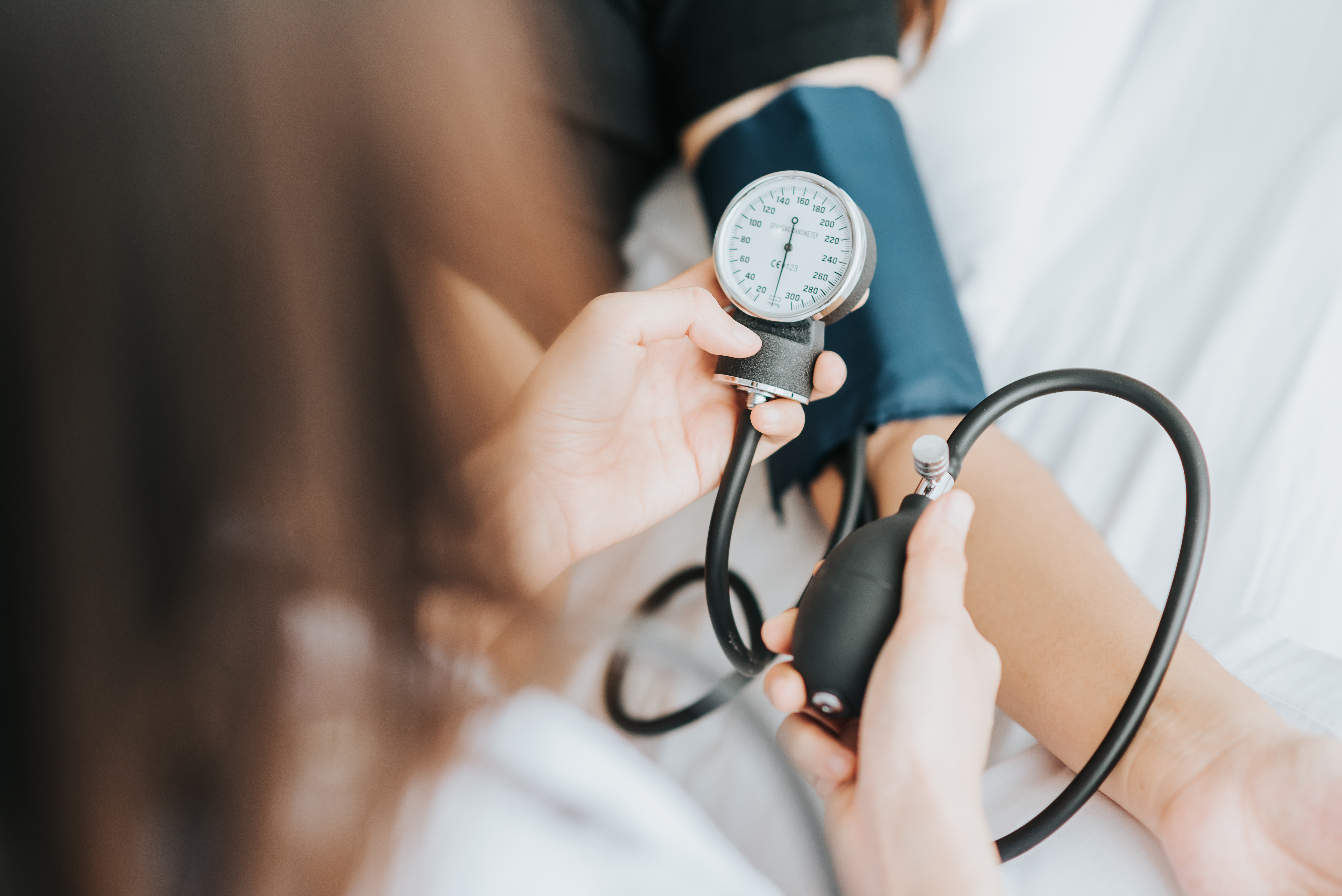 person placing blood pressure cuff on arm and checking pressure reader