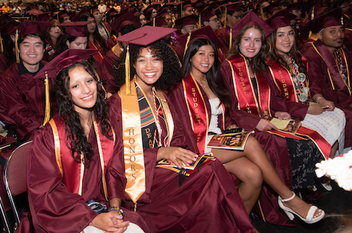 several smiling grads seated in row