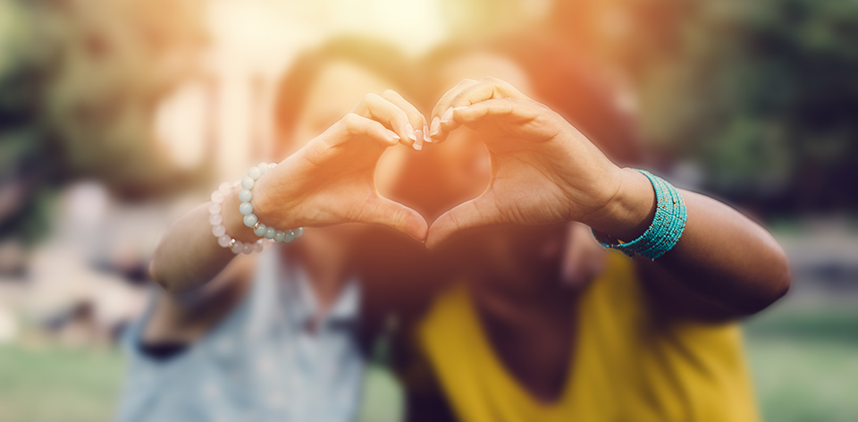 two girls making heart symbol with their hands