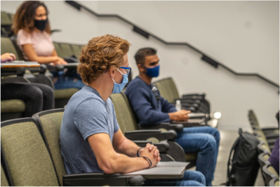 three students in seats with masks