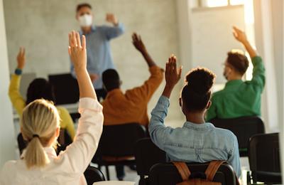 teacher with mask and students raising hands