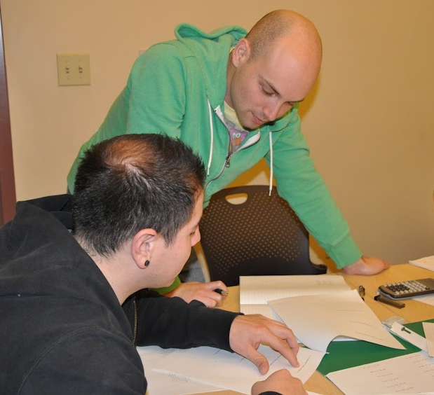 In-Class Tutoring Session male student working with male student with papers and books on table